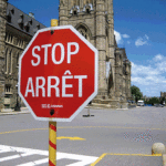 Sinal de tráfico no Canada, bilingue, onde se lê 'Stop' e 'Arrêt'.